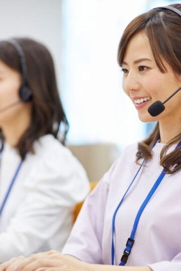 Two women wearing headsets and ID badges sit at desks in Texas, working on computers, possibly providing customer service or translation services.