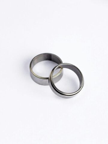 What Is a Pinky Promise Ring? Meaning, Symbolism, and Traditions Two simple silver bands overlap on a plain white background, capturing the timeless symbolism of a pinkie promise ring.