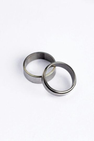 Two simple silver bands overlap on a plain white background, capturing the timeless symbolism of a pinkie promise ring.