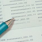 A close-up of a bank passbook shows printed transaction amounts and a blue pen pointing at a row displaying a balance of 1,800.00, similar to reviewing your credit card statement for guidance on tracking financial activity.